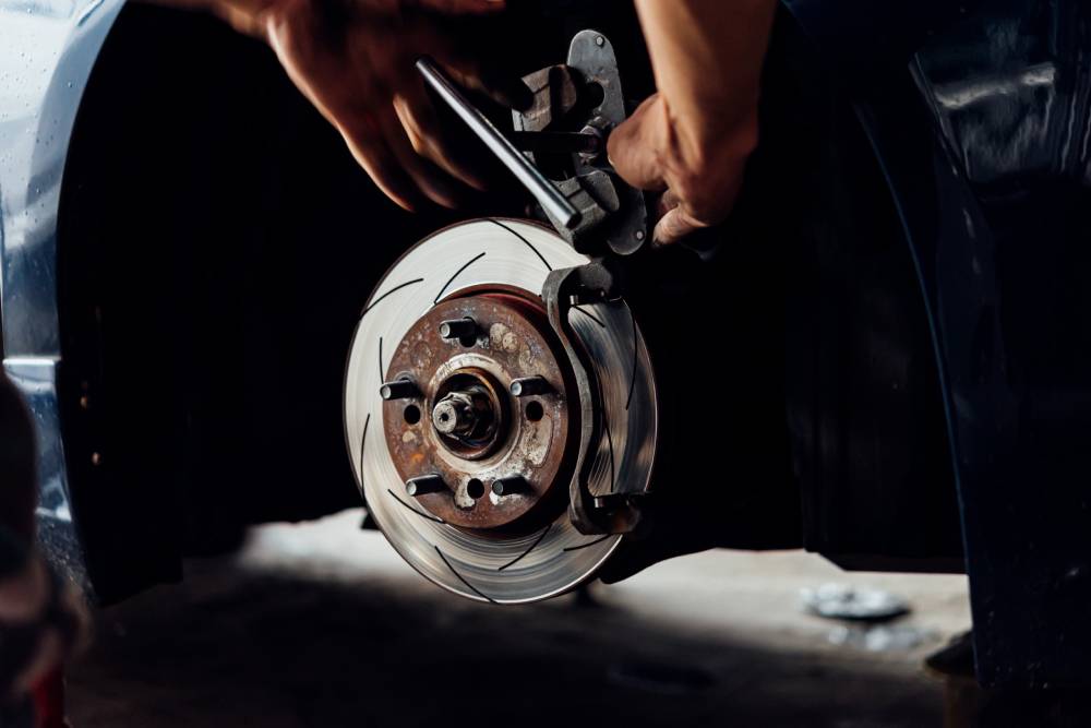 Car mechanic or serviceman checking a disc brake and asbestos brake pads it's a part of car use for stop the car for safety at front wheel this a new spare part for repair at car garage